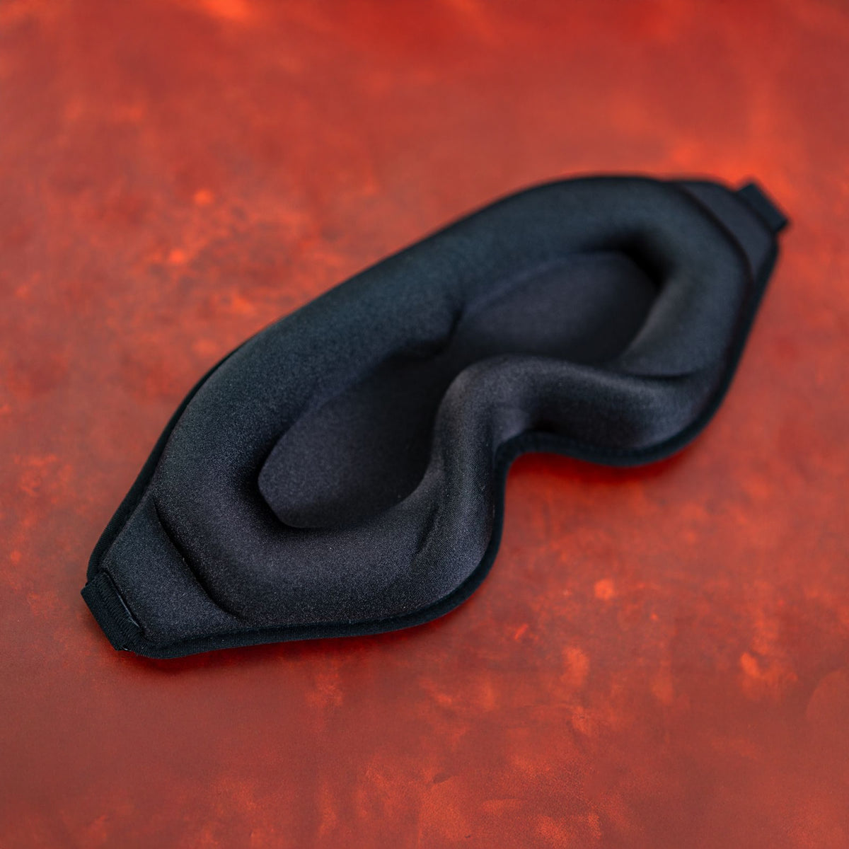Black sleep mask on a red textured background
